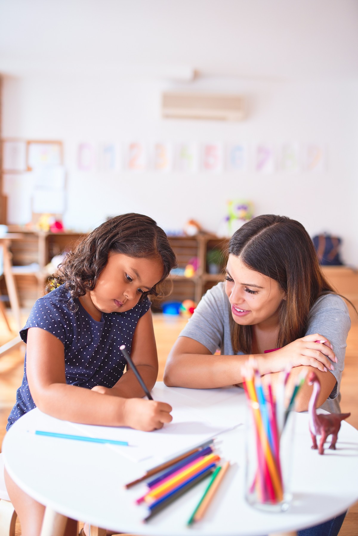 Kindergartenpädagogin und kleines Mädchen zeichnen