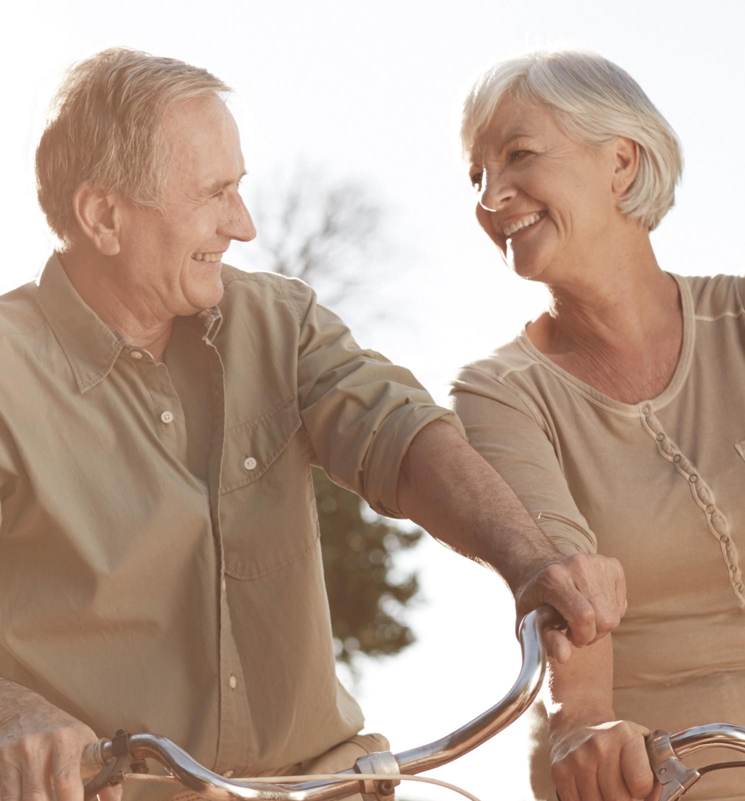 Ein älterer Mann und eine ältere Frau fahren gut gelaunt auf ihren Fahrrädern